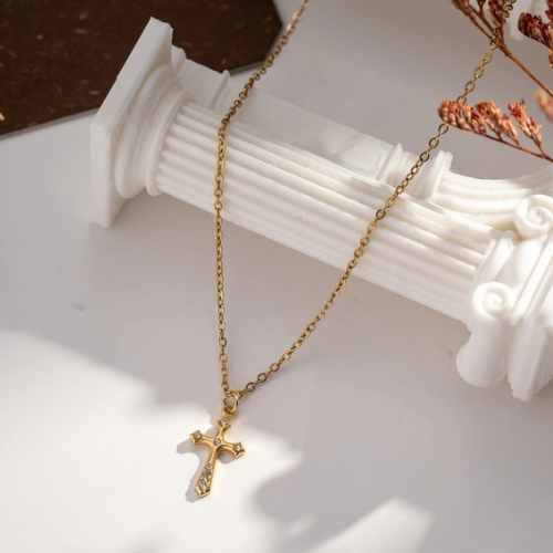 Goudkleurige ketting met kleine subtiele kruishanger ingelegd met zirkonia steentjes hangend neergelegd