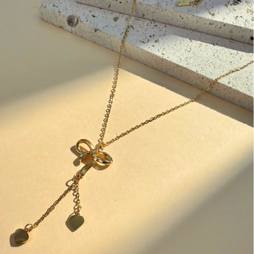 Goudkleurige Y-ketting met strikjes in het zonlicht